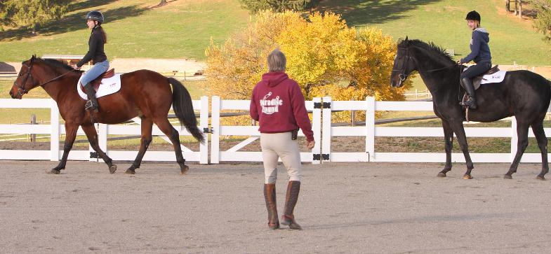 Trainer guiding two students riding horses