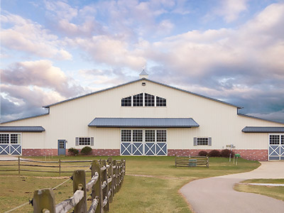A view of a horse stable building against a cloudy sky